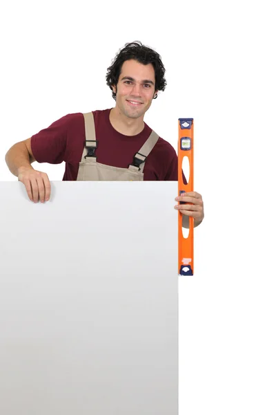 Handyman with poster and spirit-level — Stock Photo, Image