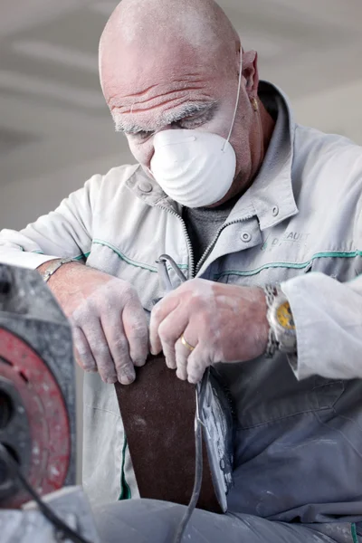 Zakurzone człowiek zmienia papier na szlifierka elektryczna — Zdjęcie stockowe