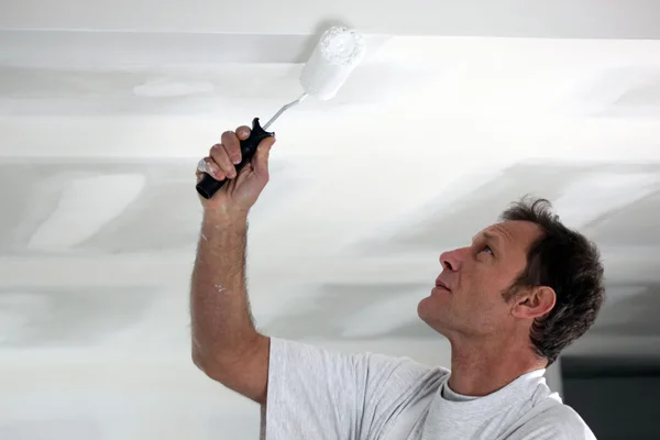 Muž maluje jeho strop bílý — Stock fotografie