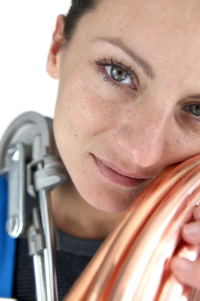 Mulher segurando tubo de cobre e ferramenta de dobra — Fotografia de Stock