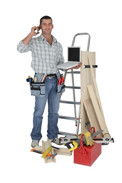 Carpenter stood with equipment making telephoning customer — Stock Photo, Image