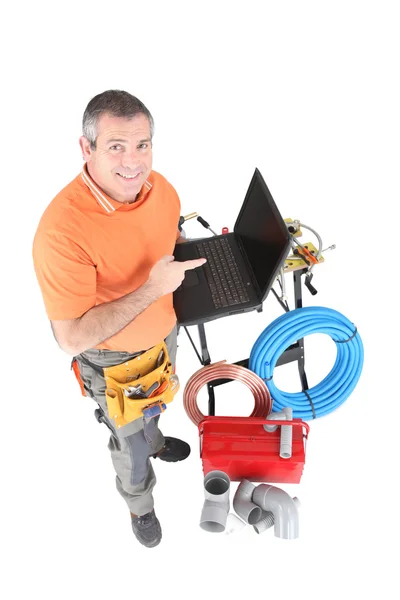 Plumber with tools and a laptop computer with a blank screen — Stock Photo, Image
