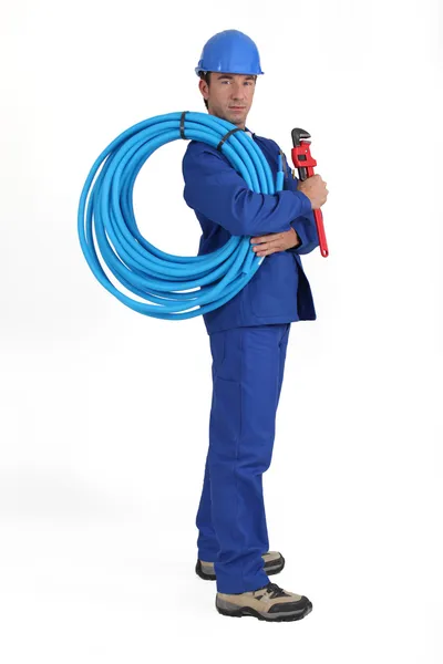 Mann mit blauem Schlauch, Schraubenschlüssel und Hut — Stockfoto