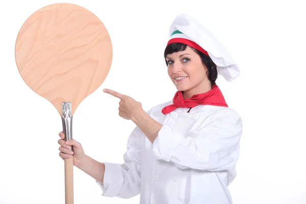 Pizza maker pointing to a pizza peel — Stock Photo, Image