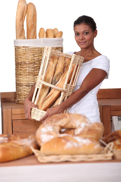 Young woman with a basket of baguettes in a baker's shop — Stock Photo, Image