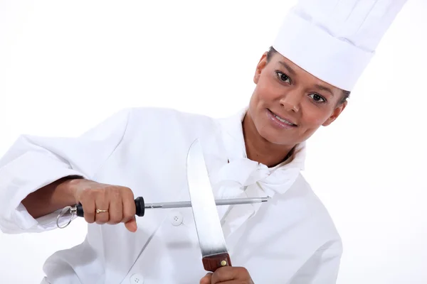 锐化一把刀的女厨师 — 图库照片