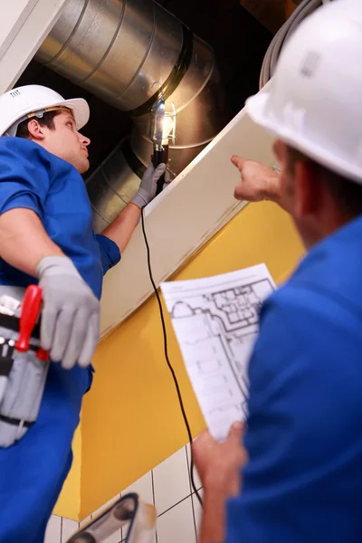 Dos trabajadores inspeccionando el sistema de ventilación — Foto de Stock