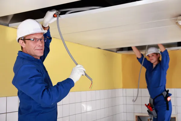 Dos electricistas trabajando en falso techo —  Fotos de Stock