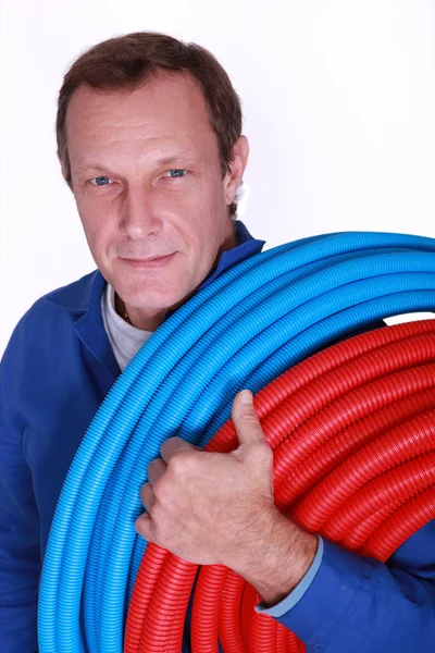 Electricista con rollos de tubo de plástico corrugado azul y rojo — Foto de Stock