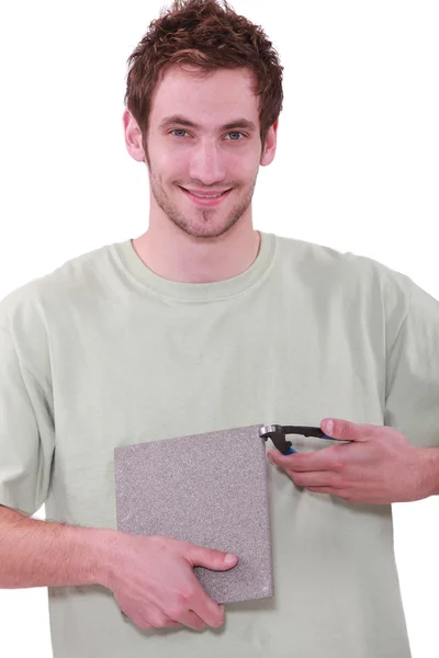 Young man holding a tile and a nipper — Stock Photo, Image