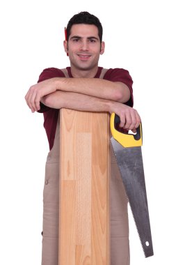 Woodworker holding a board and a saw clipart