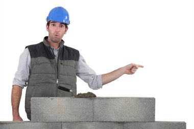 Shocked builder stood by wall pointing clipart