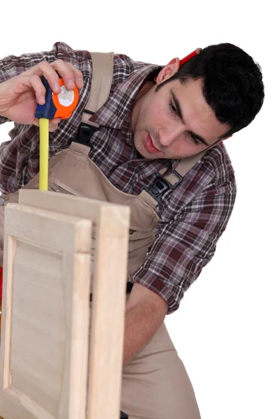 Carpinteiro medindo uma peça de mobiliário — Fotografia de Stock