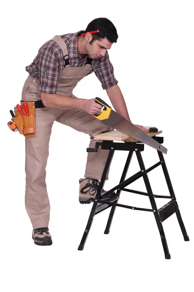 Handyman serrar uma tábua de madeira — Fotografia de Stock