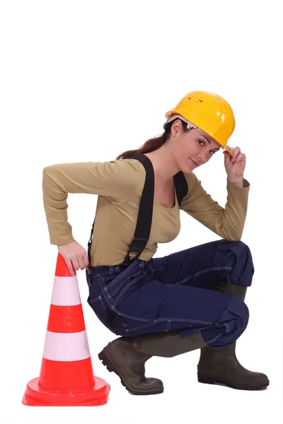 Craftswoman ajoelhado ao lado de um cone de tráfego — Fotografia de Stock