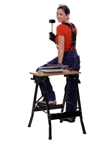 Ritratto di un montatore di piastrelle in piedi accanto a un banco da lavoro e con in mano un martello — Foto Stock