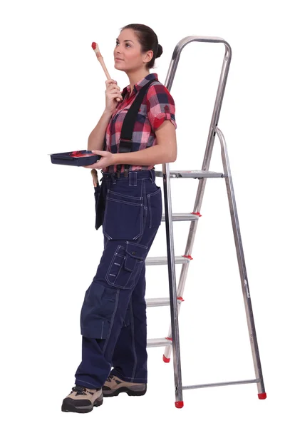 年轻女子站在梯子上用油漆刷 — 图库照片