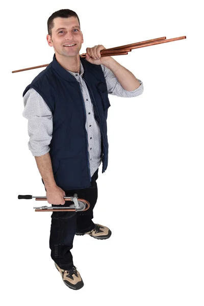 Plumber posing with copper pipes over his shoulder — Stock Photo, Image