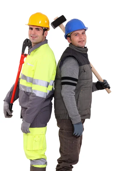 Tradesmen standing back to back and holding tools — Stock Photo, Image