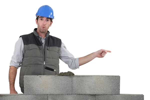 Shocked builder stood by wall pointing — Stock Photo, Image