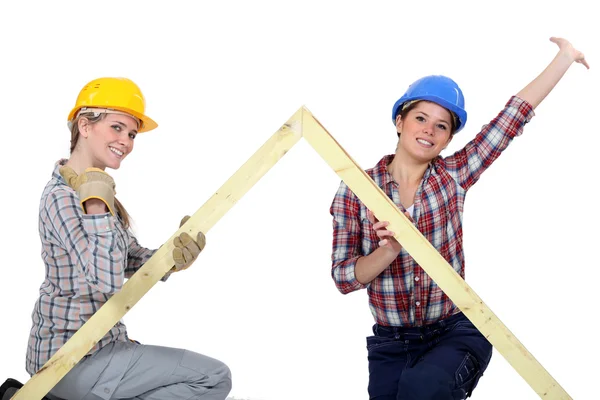 Peppy tradeswomen holding up a wooden frame — Stock Photo, Image