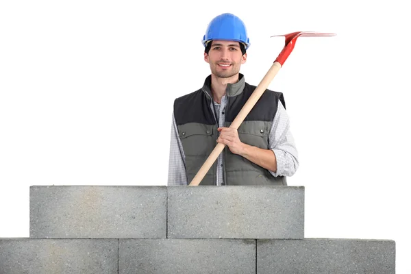 Homem com pá atrás da parede de concreto — Fotografia de Stock