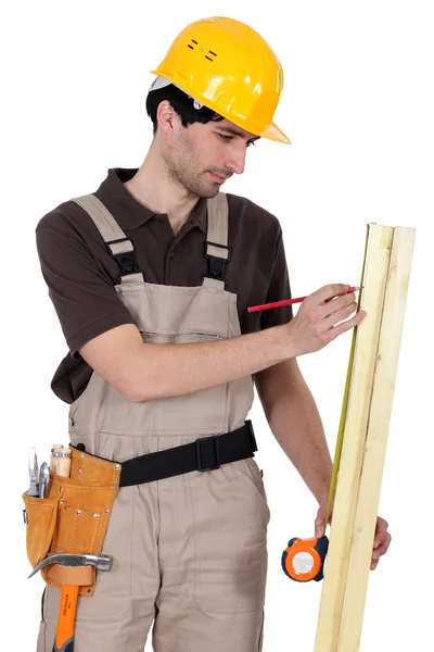 Tradesman measuring a plank of wood — Stock Photo, Image