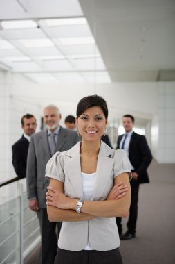 Smiling businesswoman standing cross-armed in workplace clipart