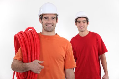 Plumber and assistant stood with coil clipart