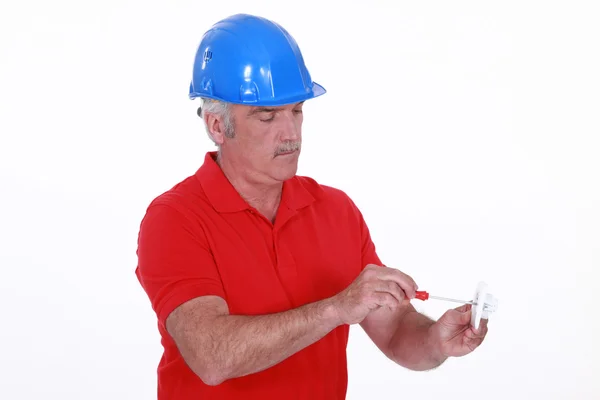 Craftsman holding a screwdriver and an electric socket — Stock Photo, Image