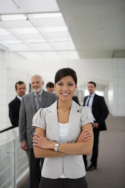 Улыбающаяся деловая женщина, стоящая в кресте на рабочем месте — стоковое фото