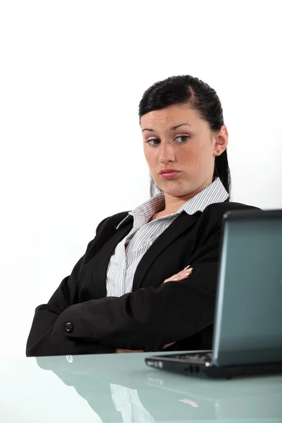 Скучная деловая женщина смотрит на свой ноутбук — стоковое фото