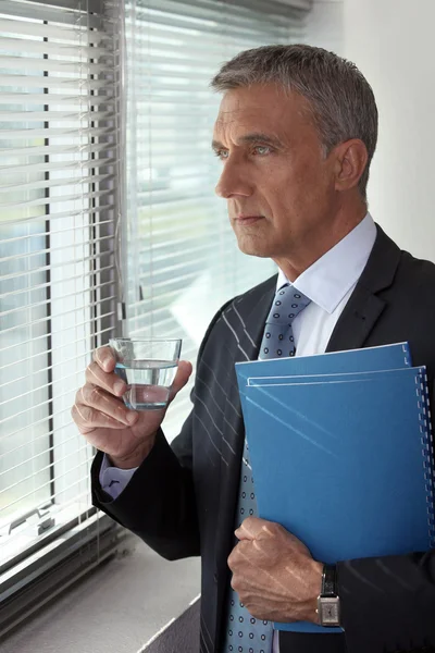 Uomo d'affari guardando attraverso la finestra del suo ufficio — Foto Stock