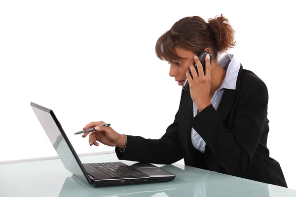 Mujer de negocios usando un ordenador portátil y teléfono — Foto de Stock