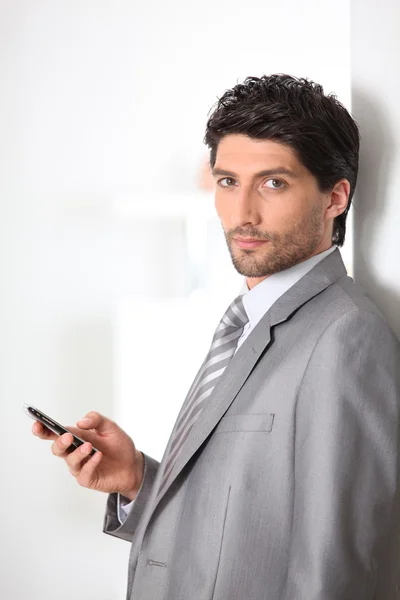 Homme d'affaires sérieux tenant un téléphone portable — Photo