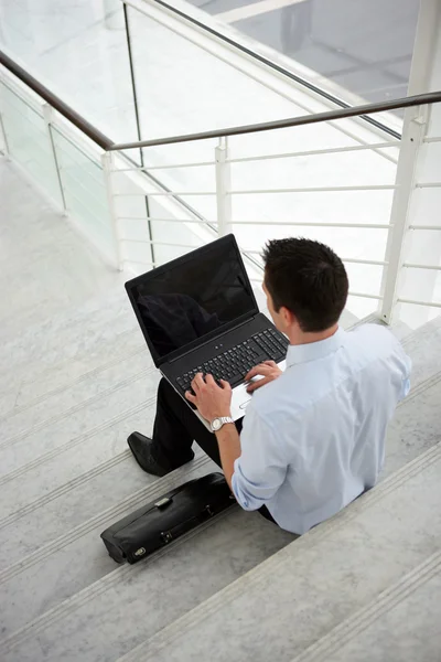 Bazı adımlar ile bir dizüstü bilgisayar üzerinde oturan işadamı — Stok fotoğraf