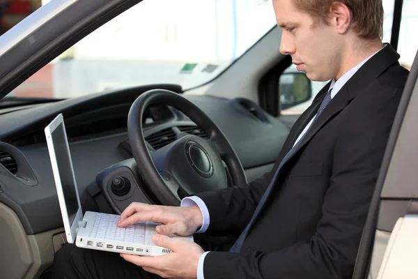 Бизнесмен использует ноутбук в своей машине — стоковое фото