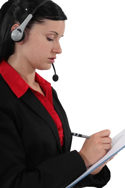 Frau mit Kopfhörerschrift auf Notizblock — Stockfoto