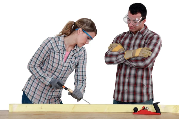 Feminino carpinteiro no trabalho com companheiro de trabalho masculino observando-a — Fotografia de Stock