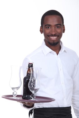 Black waiter carrying bottle of beer on tray clipart