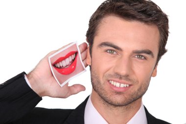 Man in a suit holding a photo of lips to his mouth clipart