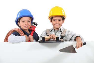 Children dressed as tradesman with a board left blank for your message clipart