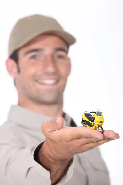 Junger Mann präsentiert ein Miniatur-Rollermodell — Stockfoto