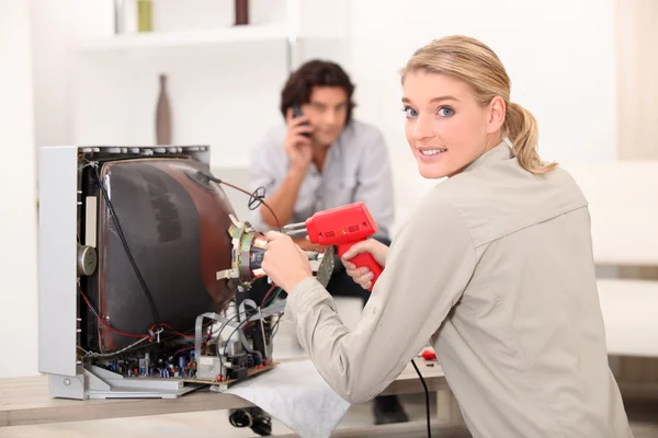 Kvinna reparera TV med lödkolv — Stockfoto