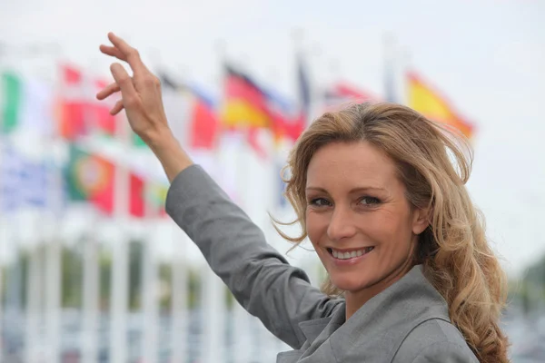 Kvinna som pekar flaggor i bakgrunden — Stockfoto
