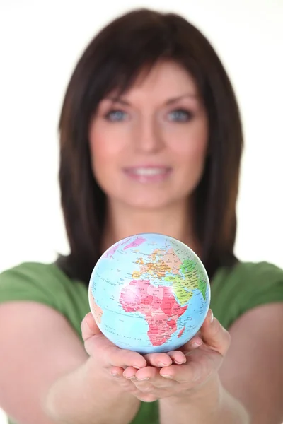 Женщина в зеленом держит планету Земля — стоковое фото