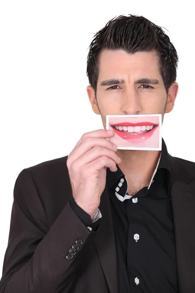 Человек в костюме держит фотографию губ у рта — стоковое фото