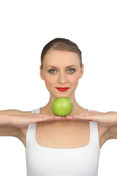 Женщина балансирует яблоко в руках — стоковое фото