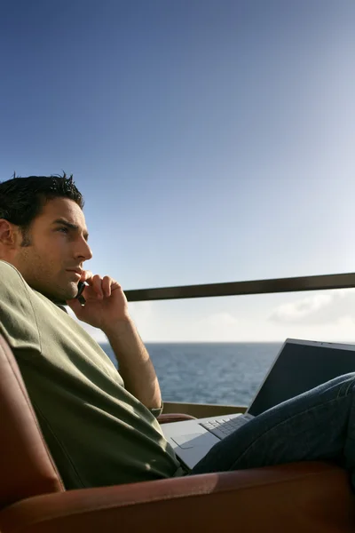 Споглядальний чоловік з ноутбуком біля океану — стокове фото