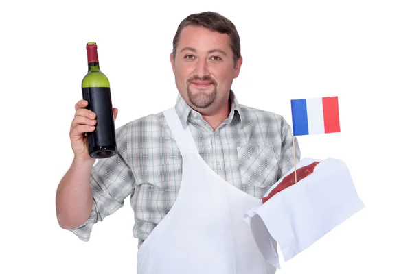 Francês com uma garrafa de tinto e um bife cru — Fotografia de Stock